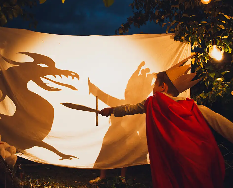 Enfant enthousiaste luttant contre un dragon de théâtre d'ombre.